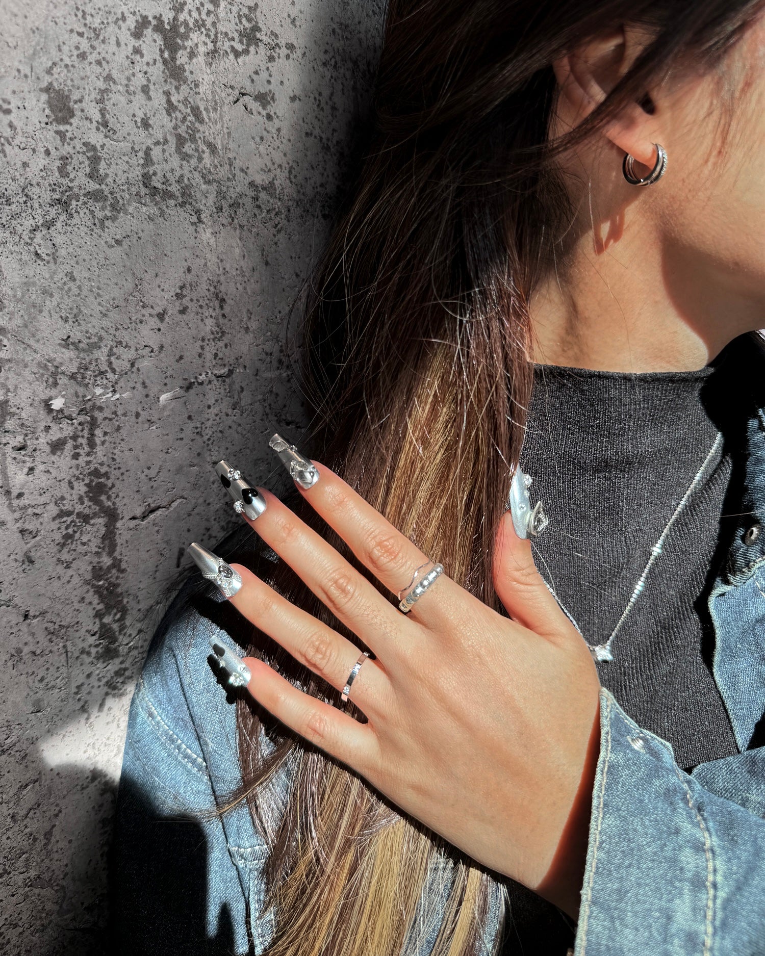 Heart Spell handmade long coffin-shaped metallic silver press-on nails with black heart design, gray heart gems, unique rhinestones, and metal chain accents