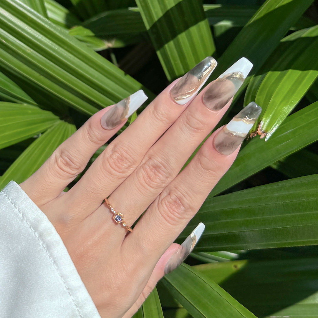 Handmade long coffin-shaped press-on nails with marble patterns and gold brushstroke accents, minimalist and elegant style