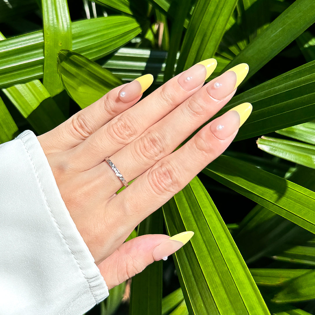 Handmade almond-shaped press-on nails with soft yellow French tips and delicate pearl accents, exuding elegance and simplicity.