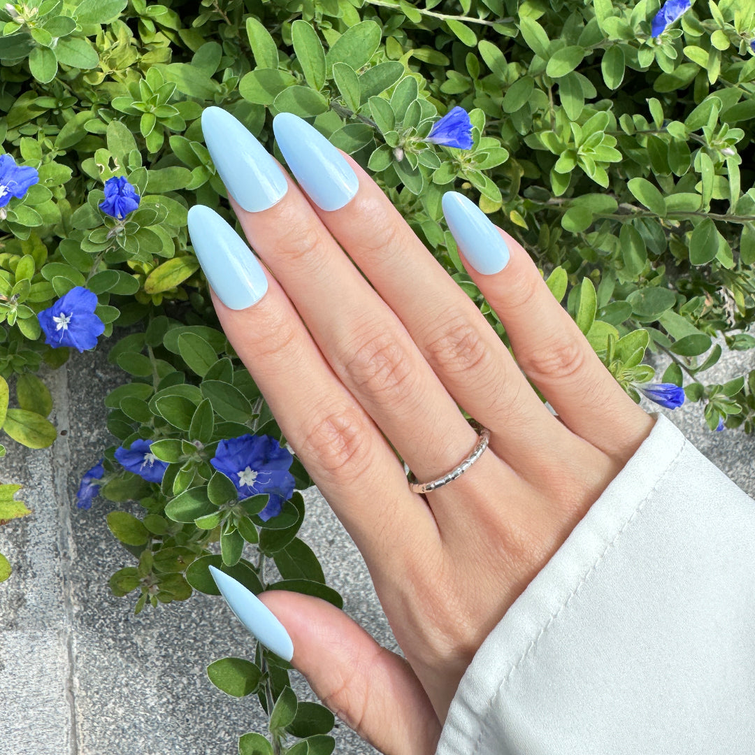 Glossy almond-shaped press-on nails in a creamy blue tone, offering a soft and dreamy finish.
