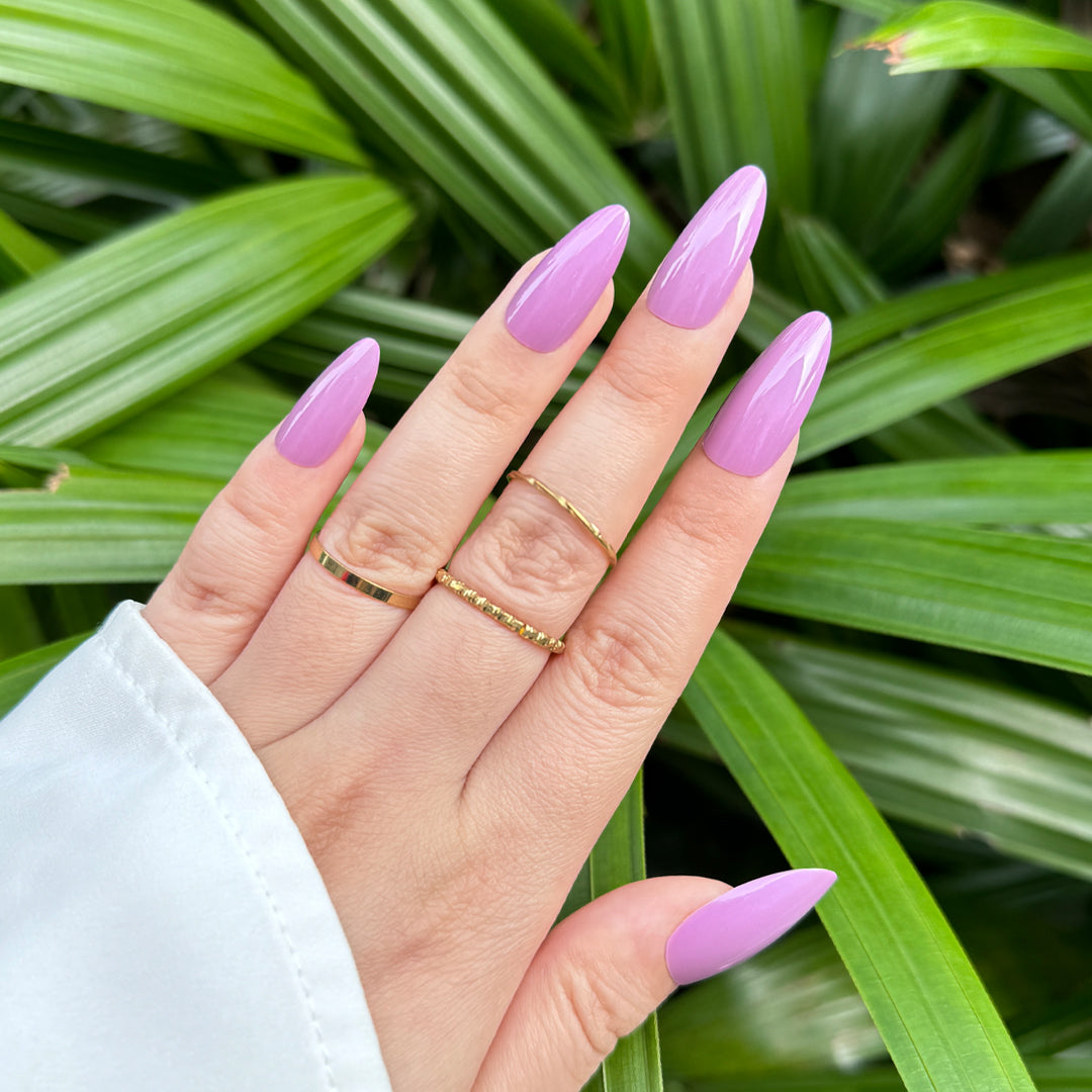Glossy almond-shaped press-on nails in a bold purple shade, perfect for making a statement.