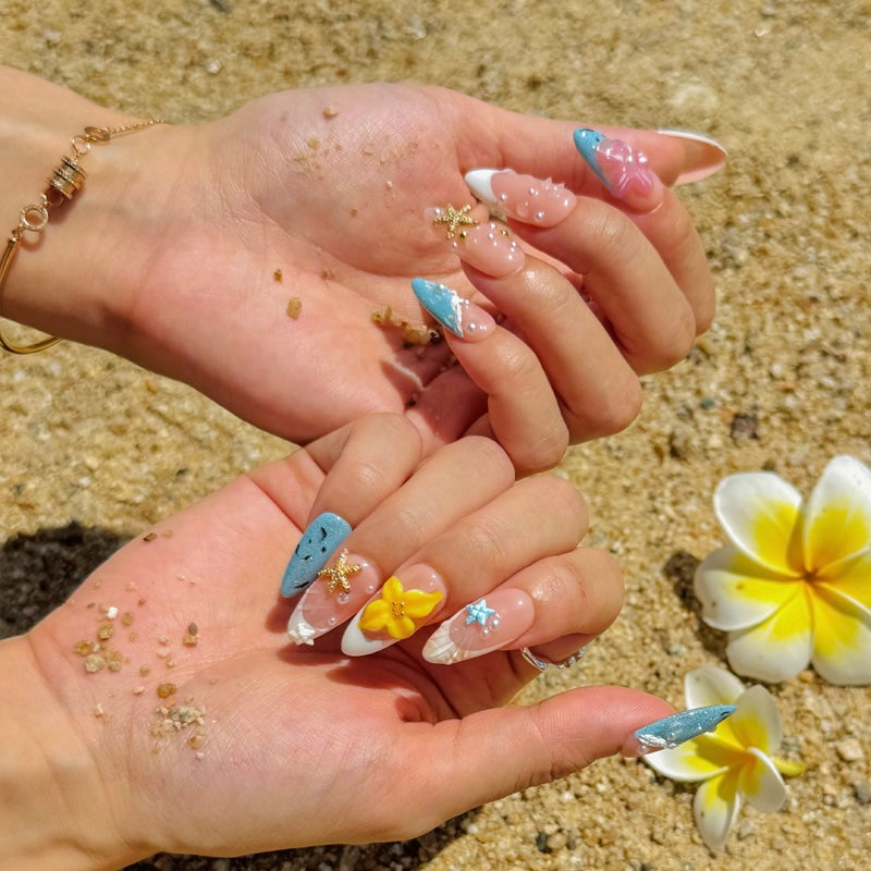 Fincloset Coastbloom almond-shaped handmade press-on nails with 3D starfish, flowers, and ocean wave elements, summer beach nail design for vacation look.