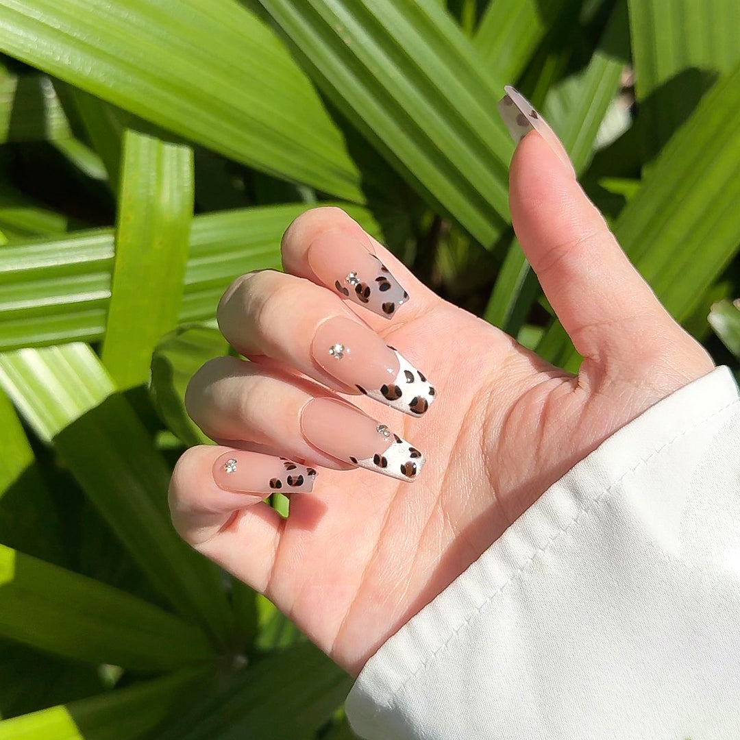 Handmade coffin-shaped press-on nails with silver French tips, brown cow print, and delicate diamond accents for a bold, stylish, and wild look.